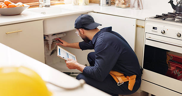 Plumber diagnosing under-sink pipes
